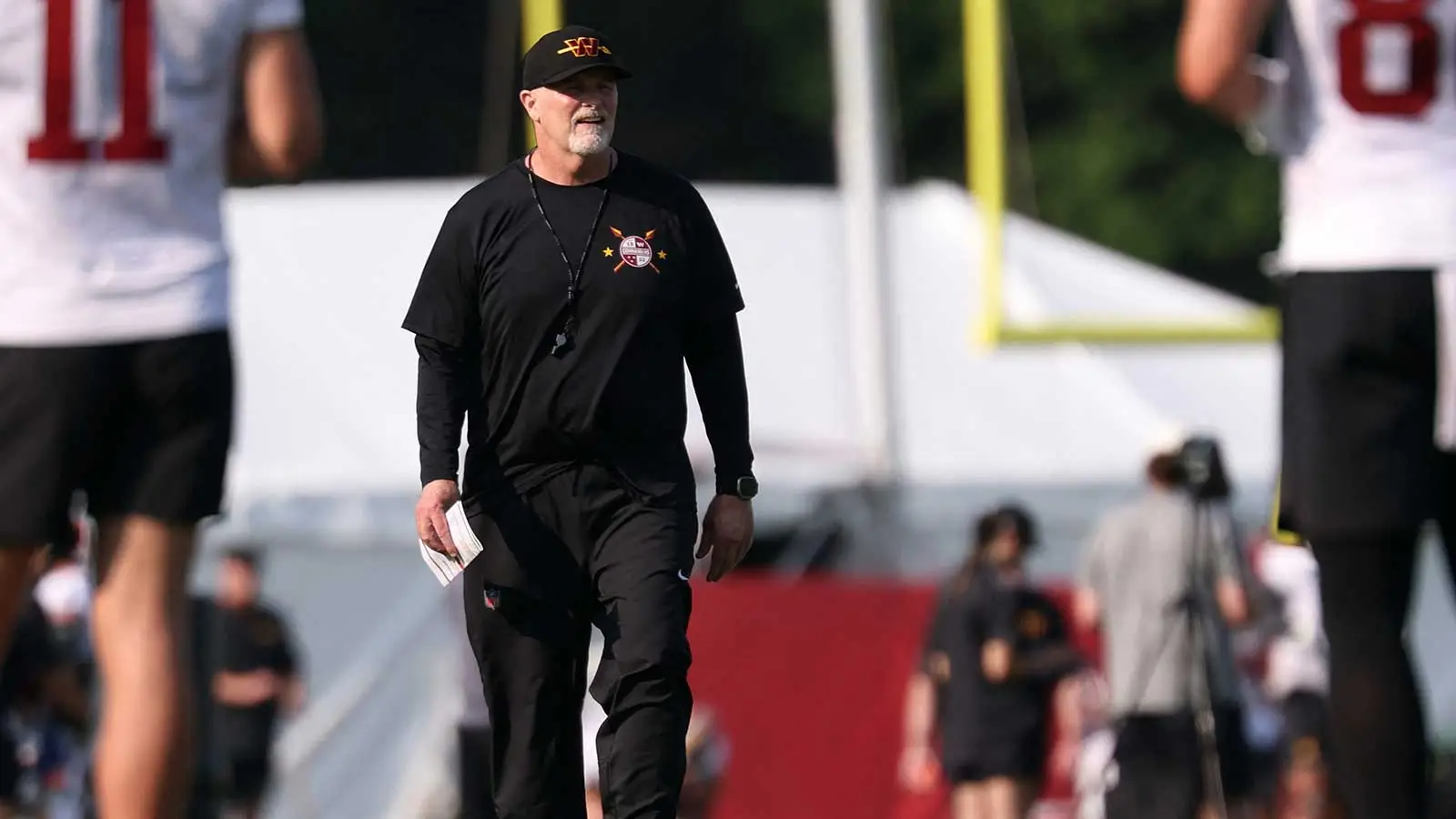 Jul 29, 2026; Ashburn, VA, USA; Washington Commanders head coach Dan Quinn walks on the field on day one of training camp at BigBear.ai Performance Center at Co…