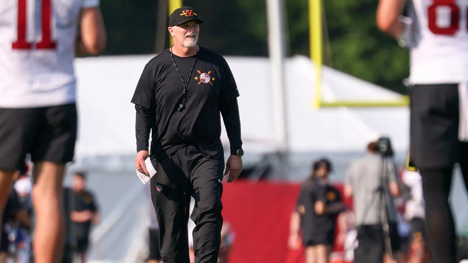 Jul 29, 2026; Ashburn, VA, USA; Washington Commanders head coach Dan Quinn walks on the field on day one of training camp at BigBear.ai Performance Center at Co…