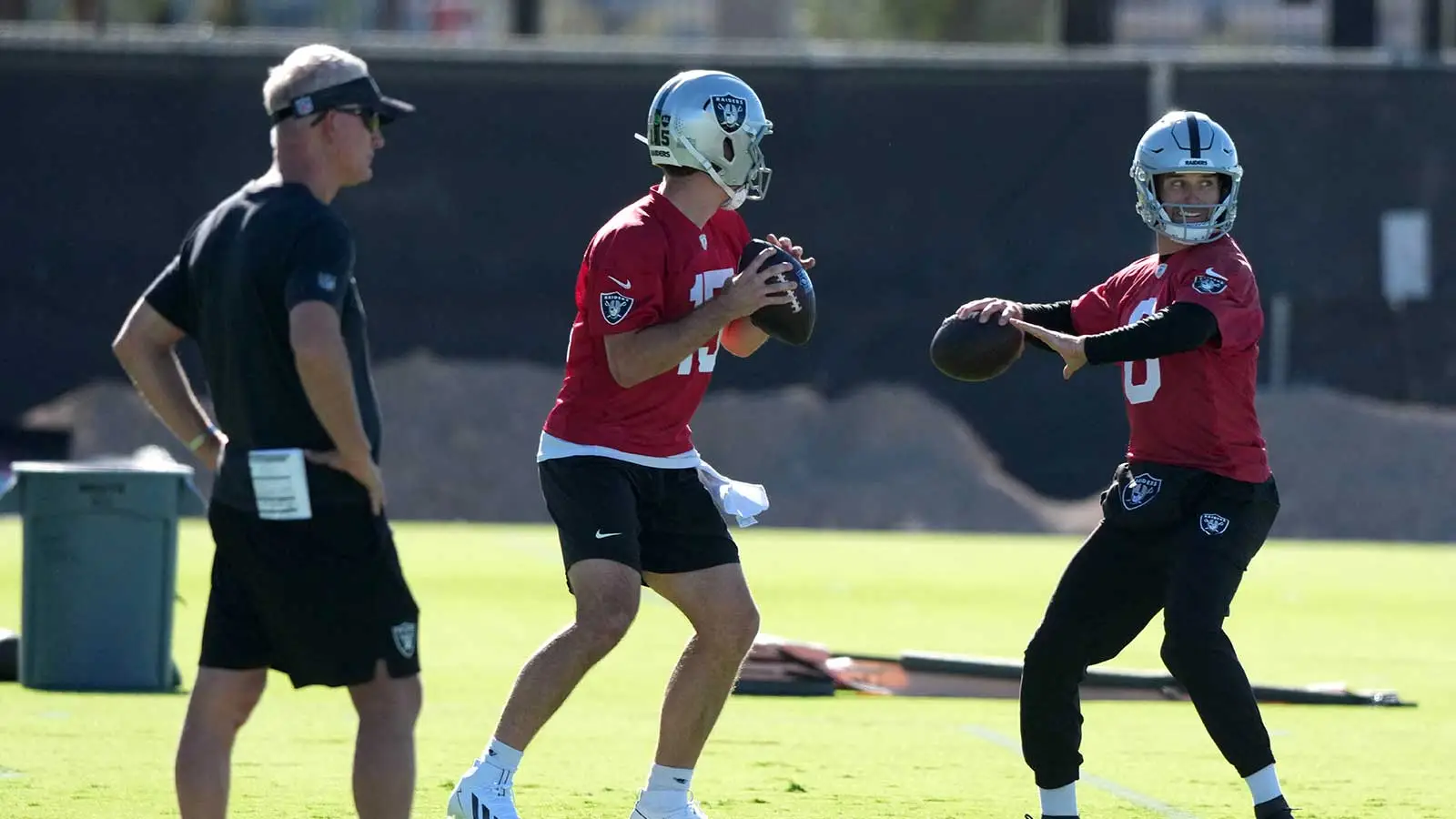 Jun 9, 2026; Henderson, NV, USA; Las Vegas Raiders quarterbacks Fernando Mendoza (15) and Kirk Cousins (8) throw the ball as assistant head coach Mike McCoy (le…