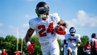 Atlanta Falcons players in full pads walking onto the practice field during training camp